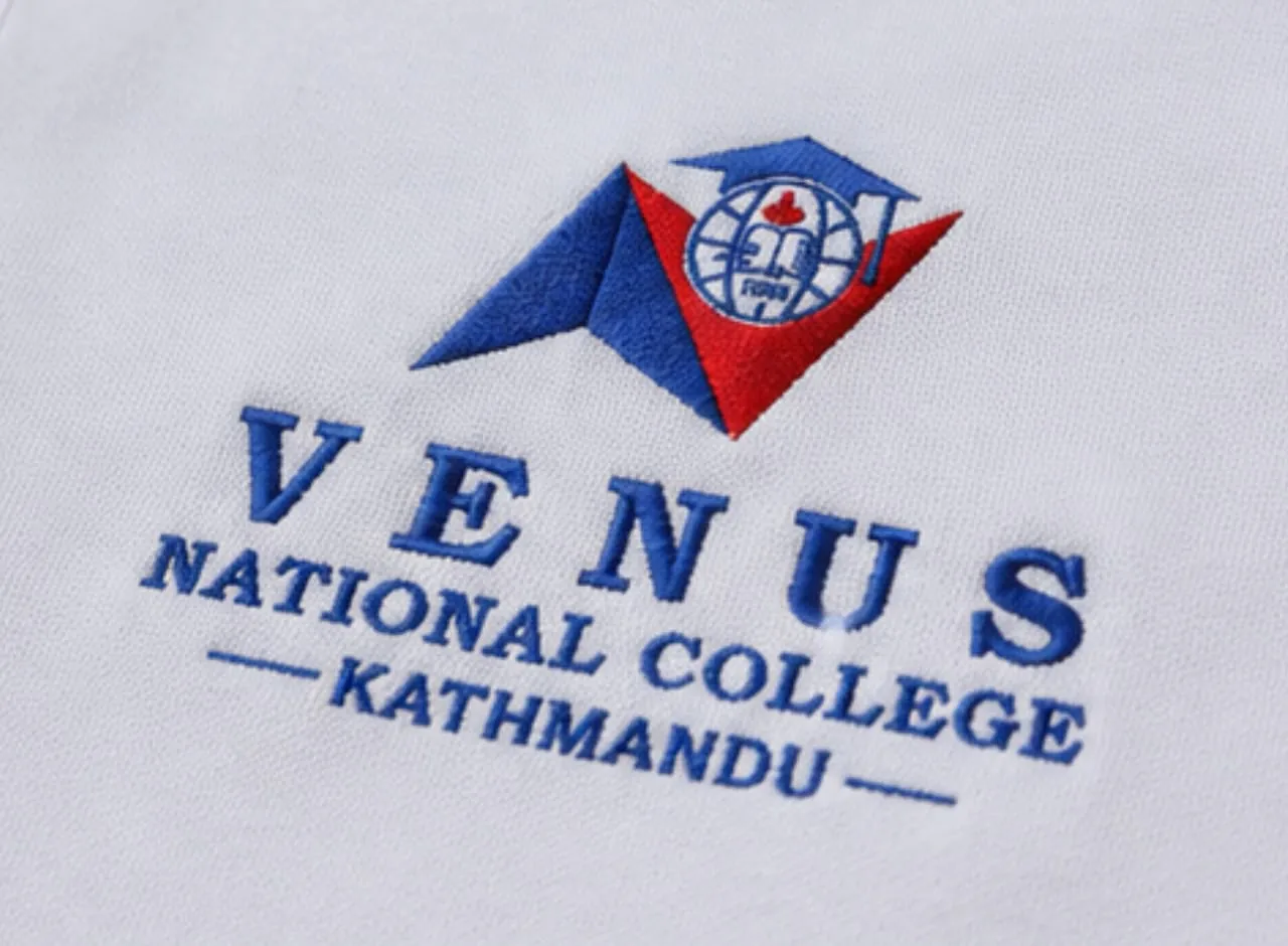 Close-up of the embroidered Venus National College Kathmandu logo on white fabric